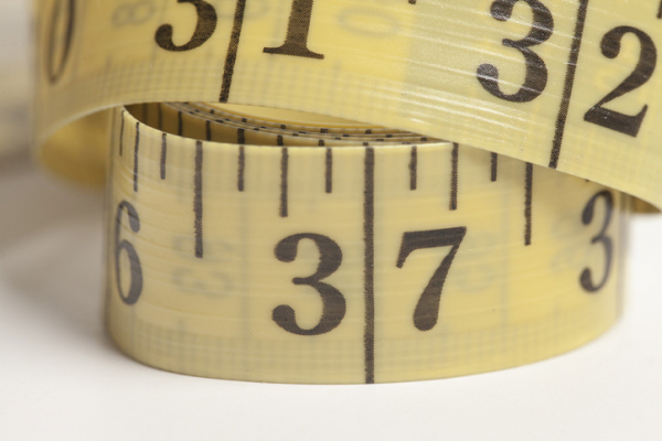 Yellow measuring tape showing black numbers "32" and "37," partial numbers, and fraction of inch markings 